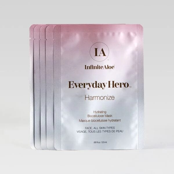 Five silver Harmonize mask 5-pack sachets, featuring gold and black text, are fanned out on a light gray background.